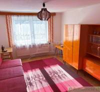 A living room in a family house with a colorful carpet, a red couch, and wooden furniture.