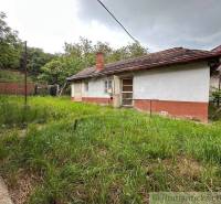 A cottage in Nové Zámky with a grassy garden and a simple facade, surrounded by greenery.