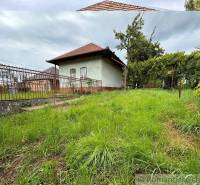 A cottage with a spacious garden in Nové Zámky, surrounded by a fence and trees.