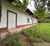 A cottage in Nové Zámky with a lawn, trees, and a white facade.