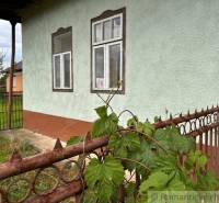 A cottage in Nové Zámky with a metal fence and green plants in the front garden.