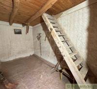 Wooden stairs lead to the attic in a simple room in the cottage.