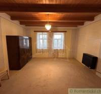 Wooden ceiling in a cabin room with simple furnishings and a central lamp.