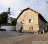 A family house near the church in Žiar nad Hronom with a large tree and power lines.
