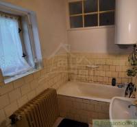 A bathroom in a family house with older tiles and an enamel bathtub.