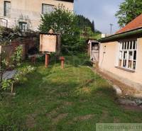 A garden at a family house in Žiar nad Hronom with a wooden bench and a shelter.