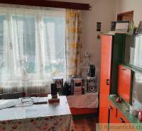 A room in a family house with a table, wardrobes, and a window with curtains.