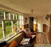 A hallway of a family house with large windows, a seating area, and a view of the garden.