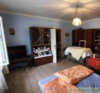 Bedroom in a family house with a bed, wooden floor, and wardrobes.