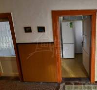 Interior of a family house with a door leading to the kitchen, visible white refrigerator.