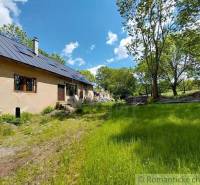 A cottage in Ábelová with a blue roof surrounded by greenery and trees.
