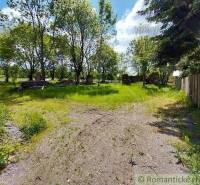 A grassy yard surrounded by trees and a wooden fence in Ábelová near the cottage.