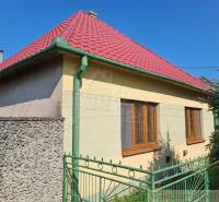 A family house in Dvorníky with a sloped roof, a green fence, and windows on the sunny side.