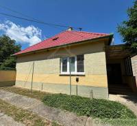 A family house in Dvorníky with a red roof and a green gate, part of the facade is yellow.