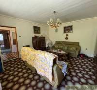 Living room in a family house with older furniture, carpet, and chandeliers.