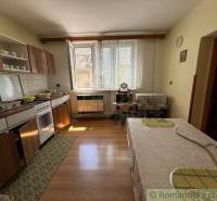 A kitchen in a family house with wooden furniture, a stove, and a dining table.