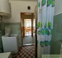 A bathroom in a family house with a washing machine, shower curtain, and gas boiler.