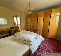 Bedroom in a family house with a bed, a large wardrobe, and a mirror on the wall.