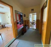 A hallway in a family house leading to a furnished kitchen and living room.