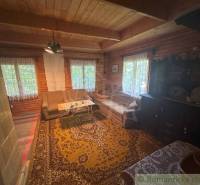 Traditional cottage interior with wooden walls, comfortable seating, and decorations.