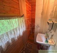 A cozy bathroom in a wooden cabin with a sink and a shower, decorated with curtains.