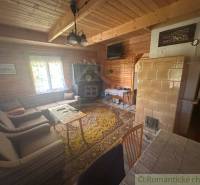 Interior of a cabin with wooden paneling, rustic furniture, and a stove for heating.
