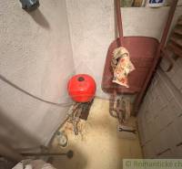 Workshop pit on a cottage with a wheelbarrow and a red expansion tank.