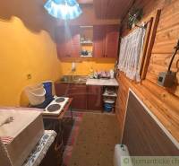 A kitchen in a cottage with wooden paneling, yellow walls, and kitchen equipment.