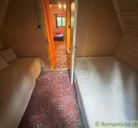 Interior of a cabin with two beds, a carpet, and a door to another room.