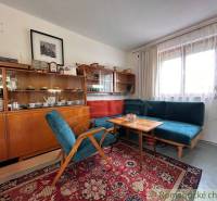 The interior of a cabin with retro furniture, a carpet, a sofa, and a display cabinet with cups.
