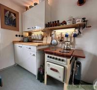 A cottage kitchen with a retro stove, a shelf, and a variety of kitchen accessories.