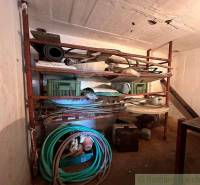 A shelf in the cottage with various tools and garden hoses.