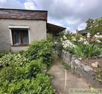 A cottage in Nové Zámky with a path lined with flowers and shrubs in the garden.