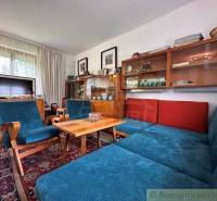 Living area of the cottage with a blue sofa, vintage furniture, and a television.