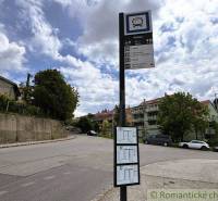 Bus stop in Bratislava-Lamač, surrounded by residential buildings and green trees.