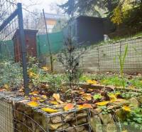 A cottage in Bratislava - Lamač with a terraced garden, gabion fence, and leaves on the ground.