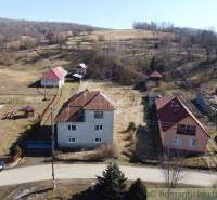 Family houses in Nová Sedlica surrounded by hills and fields with visible buildings and a road.