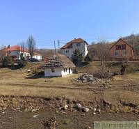 Family houses in Nová Sedlica, grassy area and a small stream in the foreground.