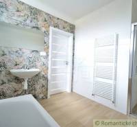 A bathroom in a family house with floral wallpaper, a sink, and a shower enclosure.