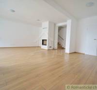 Spacious living area with wooden flooring and a fireplace in a family house.