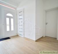 Entrance hall in a family house with wooden flooring and white doors.