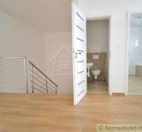 Wooden floor, two white doors, staircase, and bathroom in a family house.