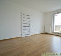 An empty room with a wooden floor and balcony doors in a family house.