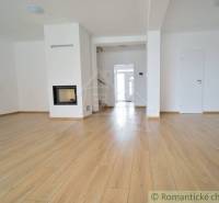 Spacious living room with a fireplace and wooden floor in a family house.