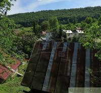 A family house in Hačava surrounded by greenery and other houses in a mountainous landscape.