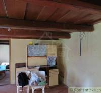A room in a family house with a wooden ceiling, old furniture, and clutter.