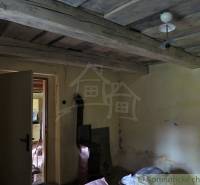 An old interior with a wooden ceiling and a tiled stove in a family house.
