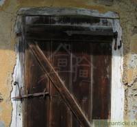 Worn wooden door in a family house in Hačava, set in peeling plaster.