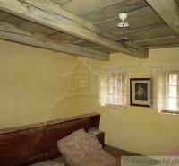 A room in a family house with a wooden ceiling, a sofa, and a portrait on the wall.