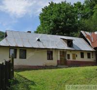 A family house in Hačava with a metal roof, surrounded by lush greenery.
